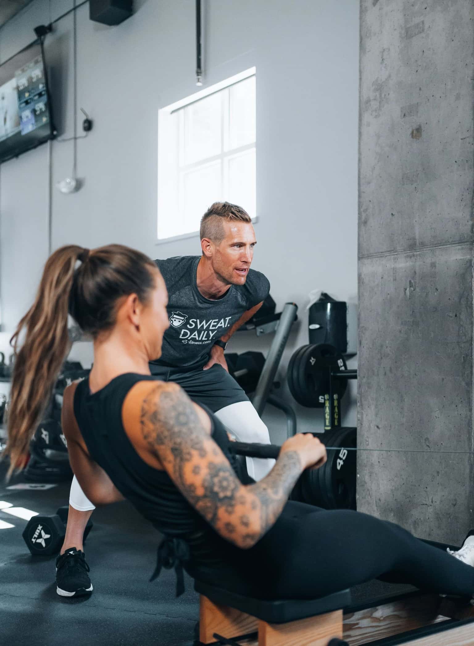 A coach guiding a client through a seated row