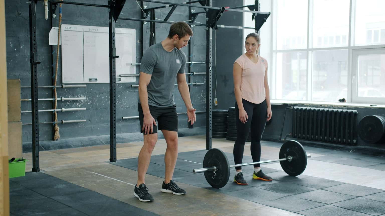 A coach walking a client through a barbell lift
