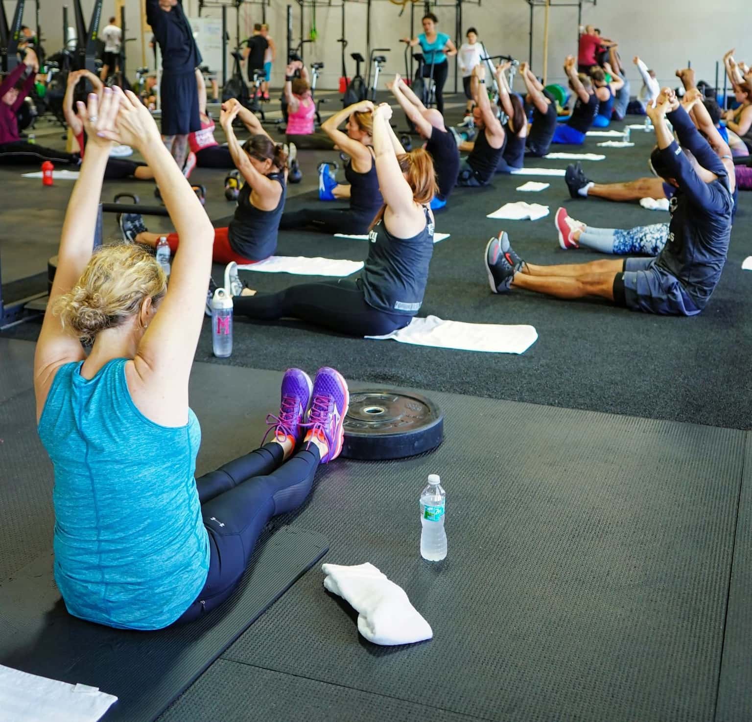 A group class stretching together on the gym floor